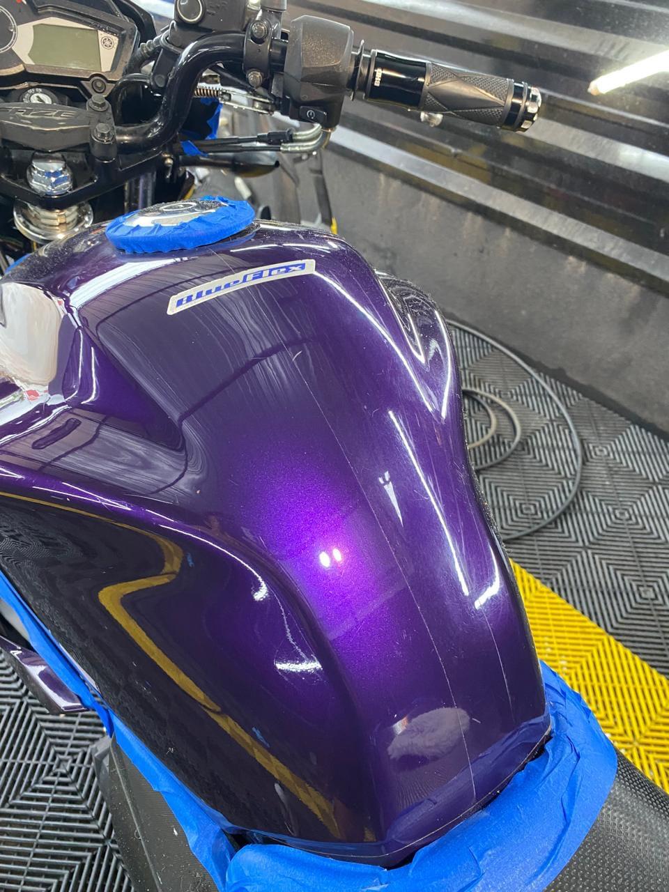 Tanque de moto roxo polido com reflexo das luzes